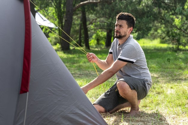 camping-travel-tourism-hike-concept-young-man-setting-up-tent-forest_169016-12839