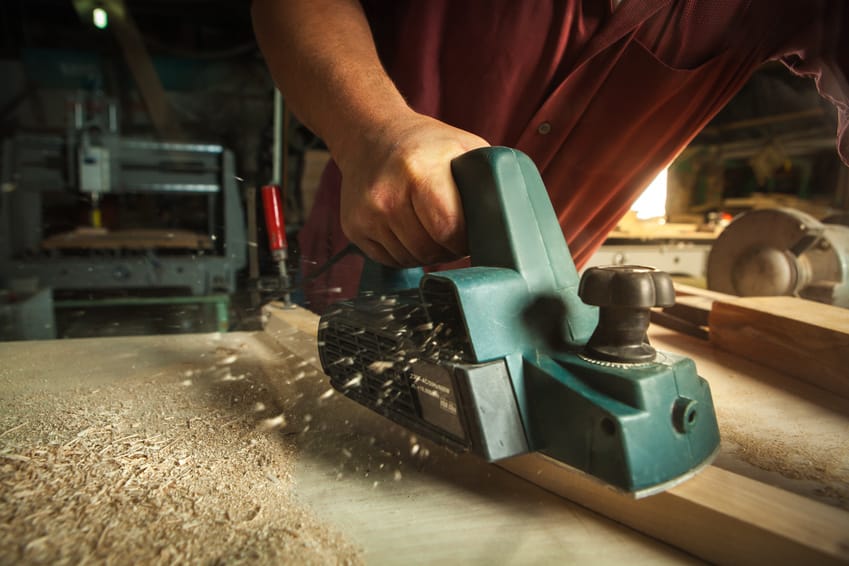 Man working with electric handheld planer