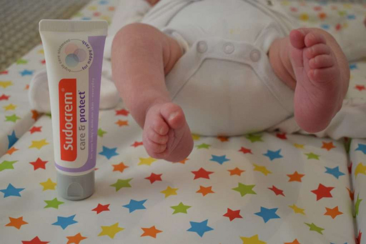 newborn baby laying beside sudocrem care and protect cream