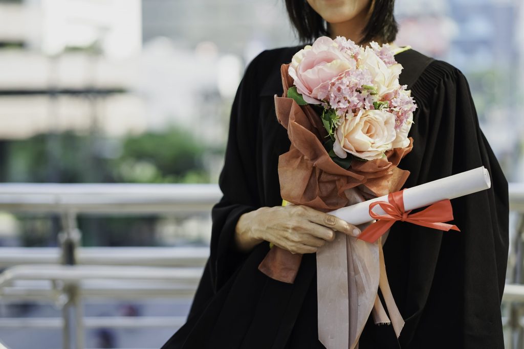 girl with graduation flowers and diploma in her hand