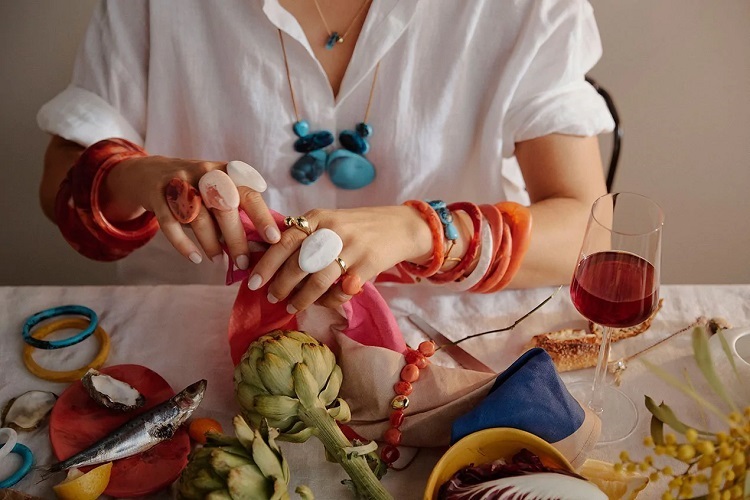 picture of a woman over a table with food and luxury resin jewellery 