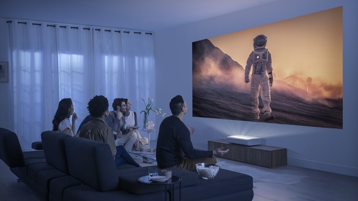 people in a small living room watching movie on a projector 