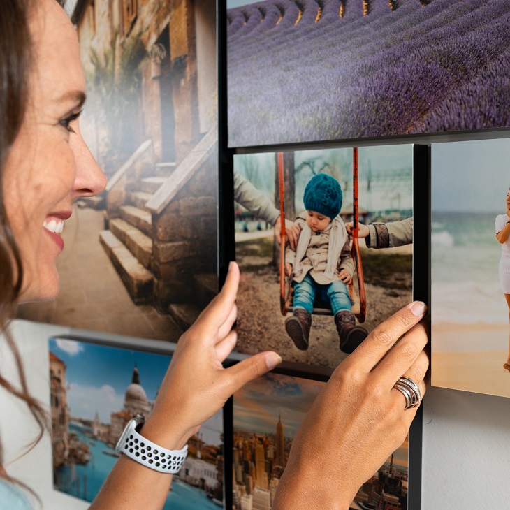 woman smiling and putting picture tiles on the wall